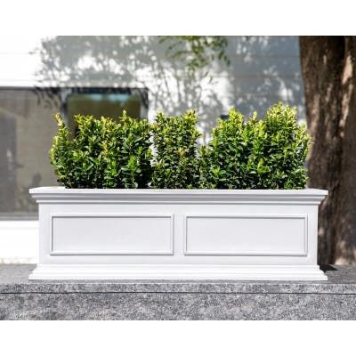 a white planter with two plants in it