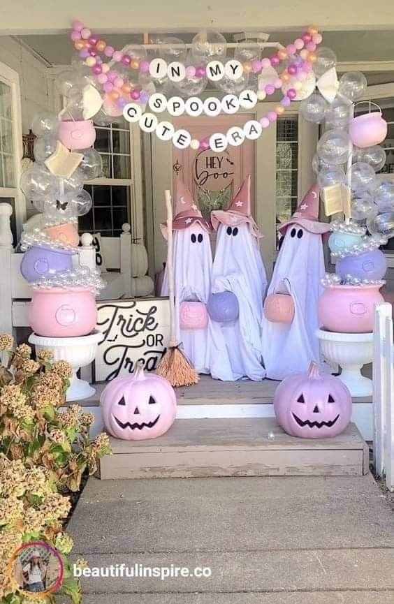 halloween decorations on the front steps of a house with ghost balloons and pumpkins around them