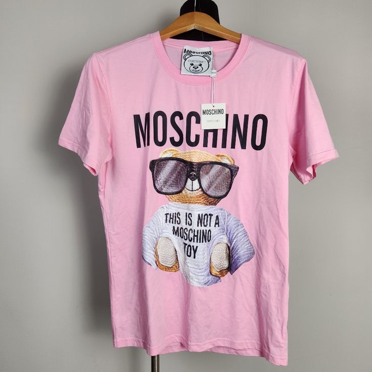 "This Is Not A Moschino Toy" Print T-Shirt From Moschino Couture. Unisex. Brand New With Tags And In Perfect Condition. *Also Available In White, See Separate Listing Designer Pink Crew Neck Tops, Designer Cotton Tops For Summer, Designer Graphic Print T-shirt For Spring, Designer Pink Short Sleeve Tops, Designer Letter Print Tops For Spring, Designer Spring Tops With Letter Print, Designer Tops With Letter Print For Spring, Pink Logo Print Shirt For Spring, Spring Pink Shirt With Logo Print