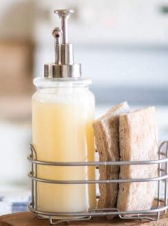 a soap dispenser sitting on top of a cutting board next to bread