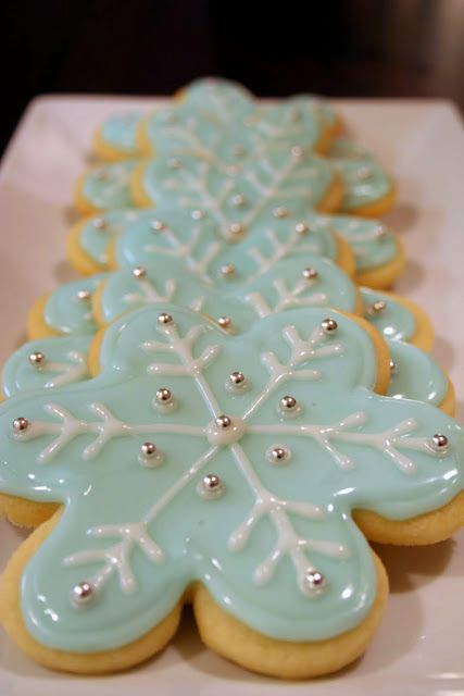 decorated cookies are lined up on a white plate with silver beaded trimmings