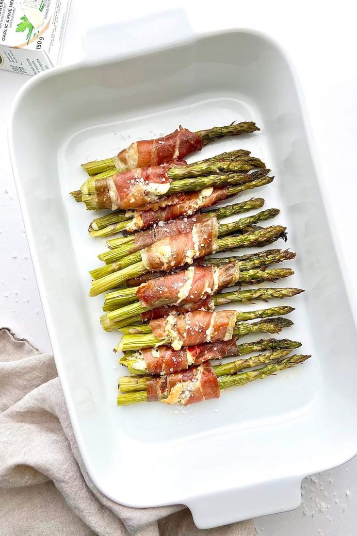 asparagus wrapped in prosciutto and bacon on a white platter