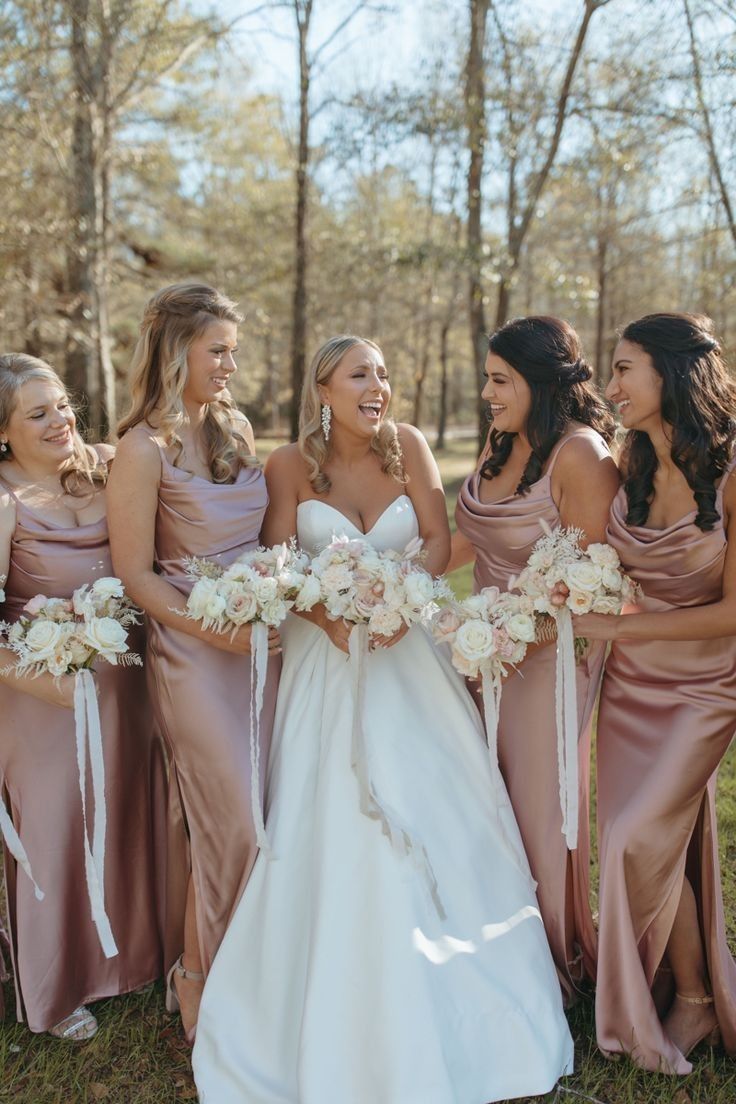 a group of women standing next to each other holding bouquets in their hands and laughing