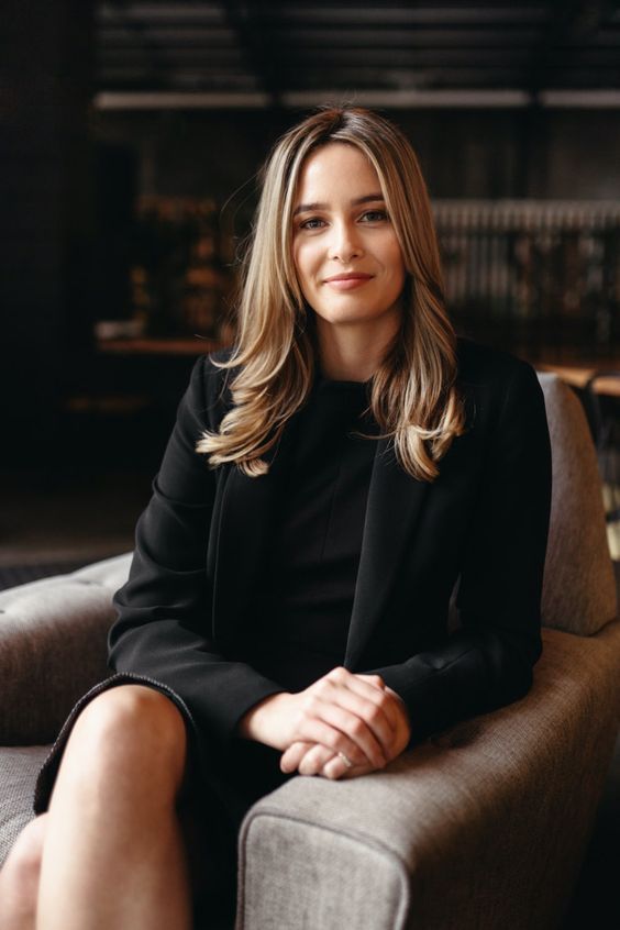 a woman sitting in a chair with her legs crossed and looking off to the side