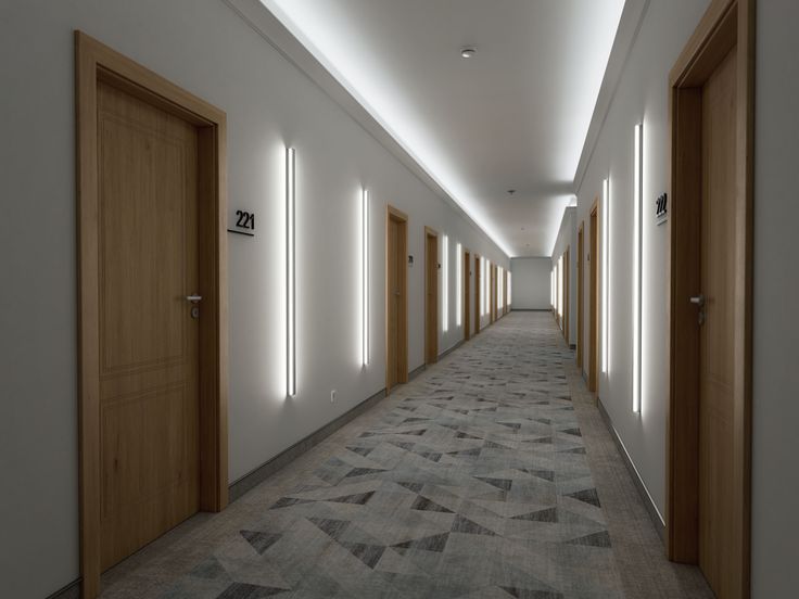 an empty hallway with several doors and lights on either side of the corridor, leading to another room