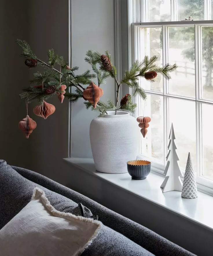 a white vase sitting on top of a window sill next to a christmas tree