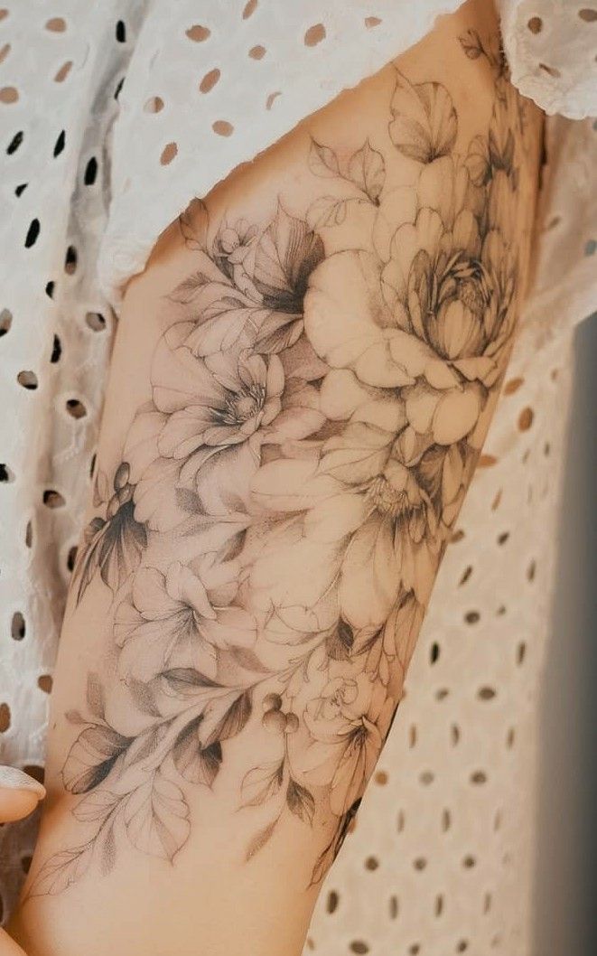 a woman's arm with flowers and leaves on the left side of her body