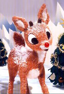 a fake deer standing in front of christmas trees with snow on it's face