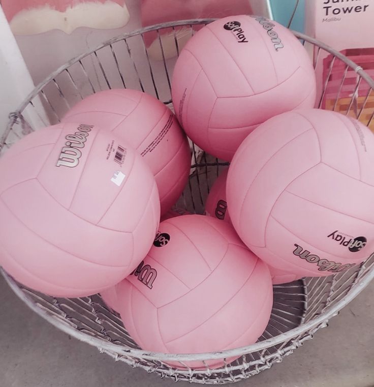 four pink volleyballs sitting in a basket