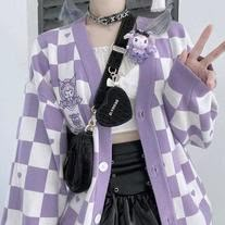 a doll wearing a purple and white checkered cardigan with a peace sign in her hand