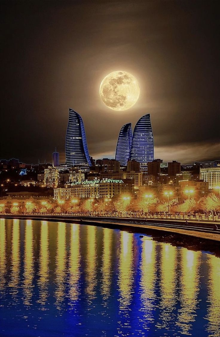 the full moon shines brightly in the night sky over a city with tall buildings