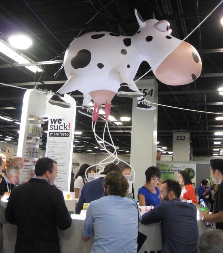 a group of people standing around a table with a cow balloon hanging from the ceiling