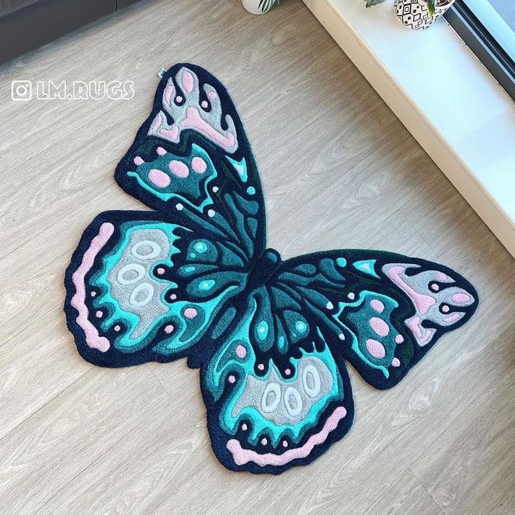 a blue and pink butterfly sitting on top of a wooden floor