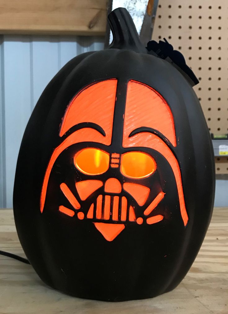 a darth vader pumpkin with glowing eyes and a star wars helmet on it