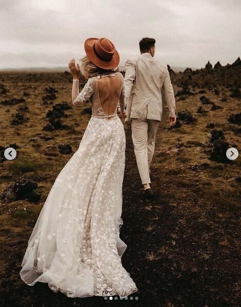 a bride and groom walking in the middle of an open field with rocks on either side