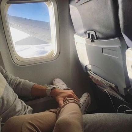 a person sitting on an airplane seat with their feet up in front of the window