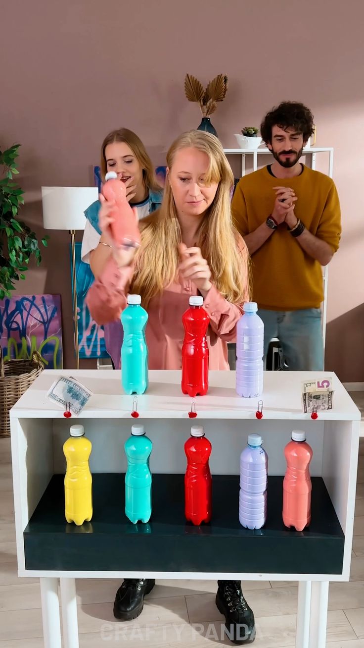 two people are standing behind a table with bottles on it and one person is pointing at something