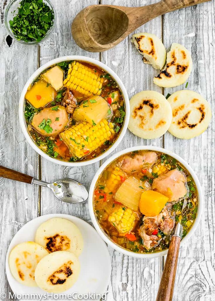 two white bowls filled with soup next to sliced bananas and other food on a wooden table