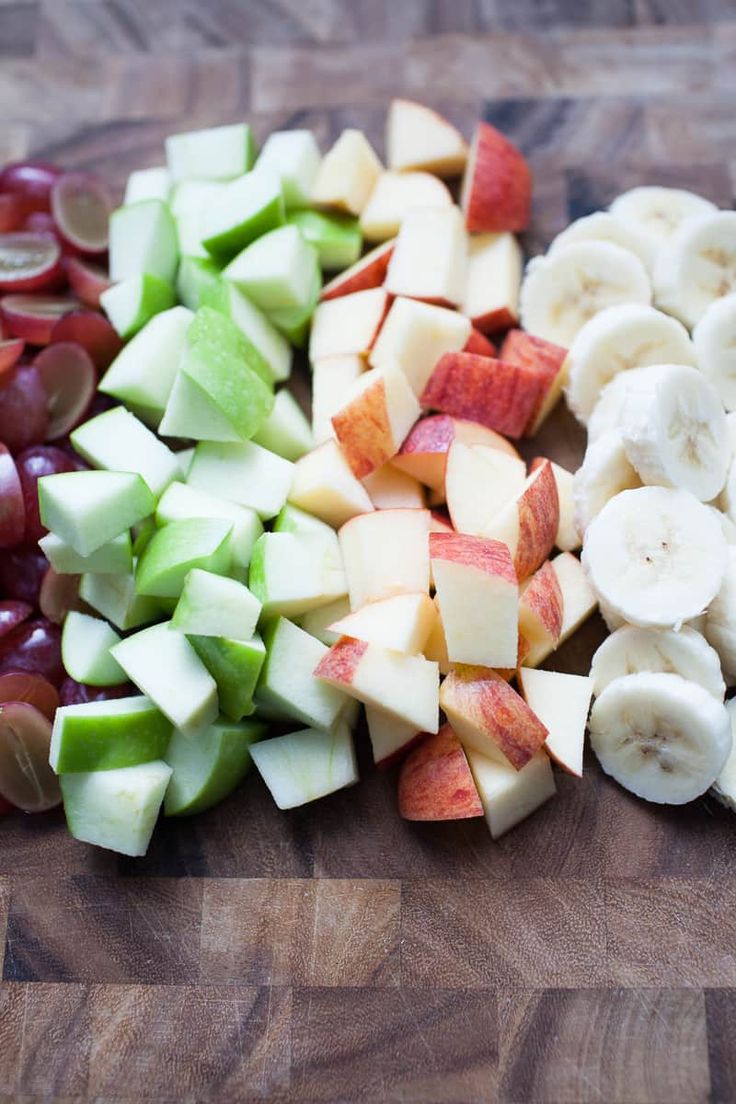 sliced apples, grapes and bananas on a cutting board