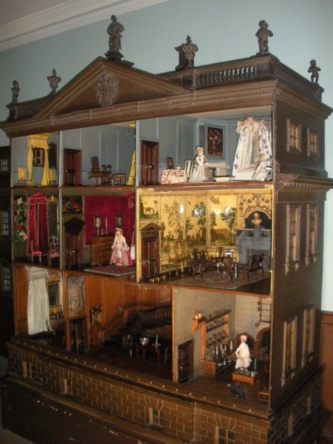 a doll house is shown with dolls in it's display case on the shelf