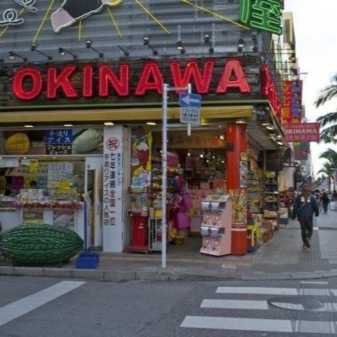 a street corner with people walking around and shops on the side of the road in front of it