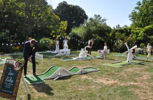 a group of people playing miniature golf in the grass