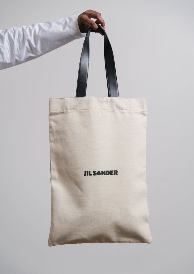 Cotton-linen blend canvas shopper bag in Natural Double buffed leather handles Printed Jil Sander branding at front Buffed leather inner pocket Made in Italy 70% cotton, 30% linen body 100% calf leather handles Jil Sander Canvas Bag, Leather Shopping Bag, Cotton Bag Design, Shopper Bag Design, Tote Bag Packaging, Canvas Tote Bag Design, Eco Bag Design, Mens Tote Bag, Branded Shopping Bags