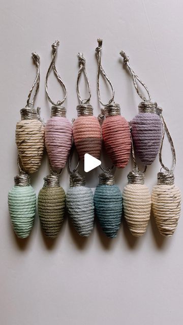 a group of multicolored paper lanterns hanging from silver hooks on a white wall