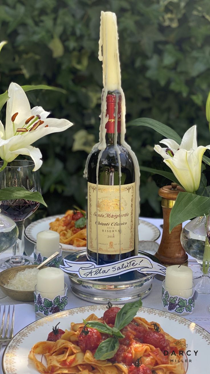 a bottle of wine sitting on top of a plate filled with pasta and sauces