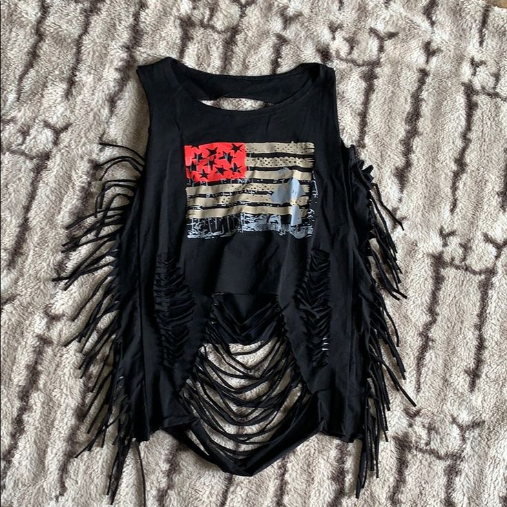 a black top with fringes on it sitting on a bed next to a pillow