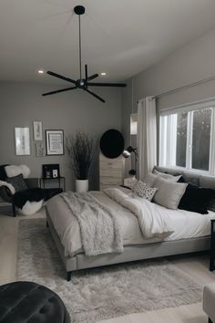 a bedroom with a large bed and two black chairs in front of the window on the far wall