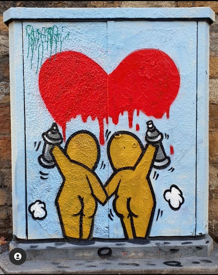 a painting on the side of a building with two people holding up a red heart