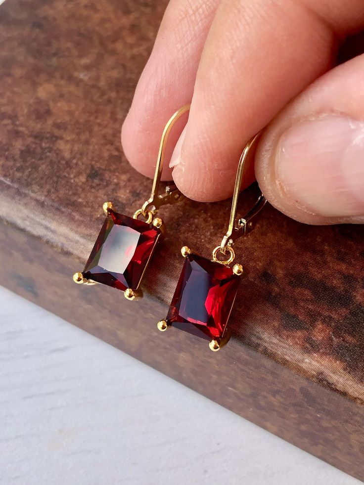 Garnet Earrings, January Birthstone, Dark Read Emerald Cut Earrings in Gold or Silver, Rectangular Baguette Drops, Garnet Jewelry for Women These elegant baguette earrings feature dark red rectangle gemstones prong set in your choice of gold filled or sterling silver. The vivid garnet emerald cut drops are suspended from lever back ear wires in the finish of your choice. These are great choice for simple yet elegant earrings to wear virtually anywhere. Ideal gift for a woman born in January, as Luxury Rectangular Garnet Jewelry, Red Faceted Earrings For Formal Occasions, Classic Rectangular Stone Earrings For Gift, Classic Earrings With Rectangular Stone For Gift, Classic Rectangular Stone Earrings As Gift, Red Rectangular Jewelry For Evening, Rectangular Red Jewelry For Evening, Red Gemstone Earrings, Simple Earrings Gold