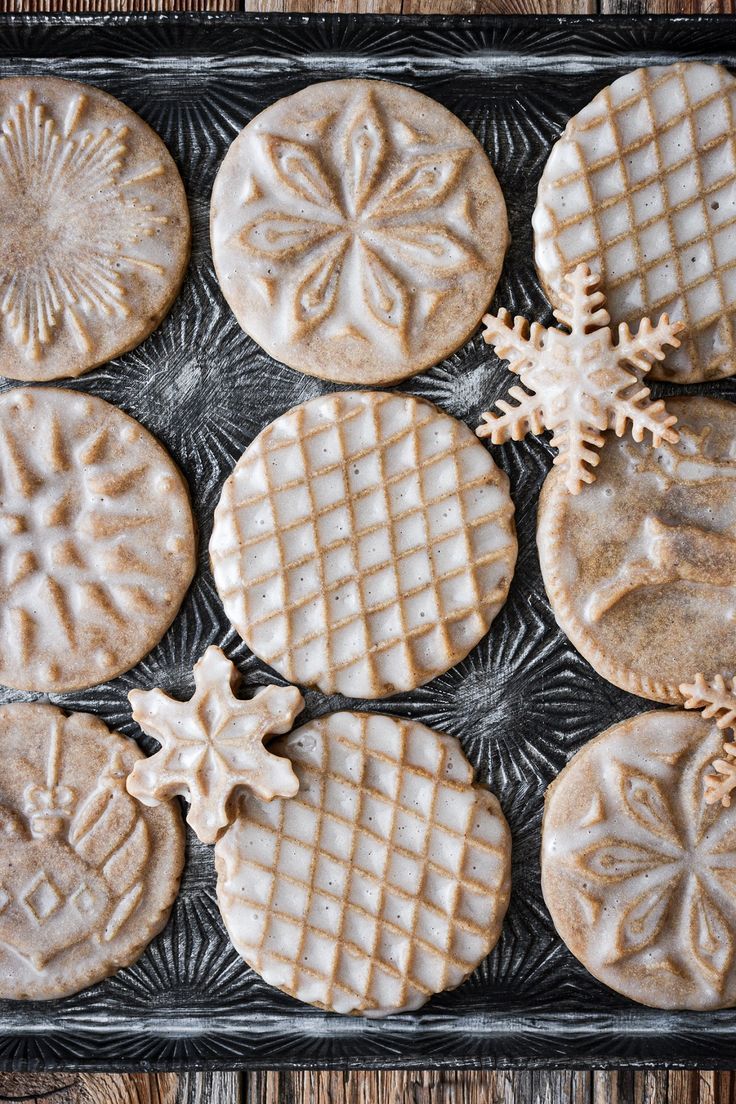 some cookies are sitting on a baking sheet with icing and snowflakes around them