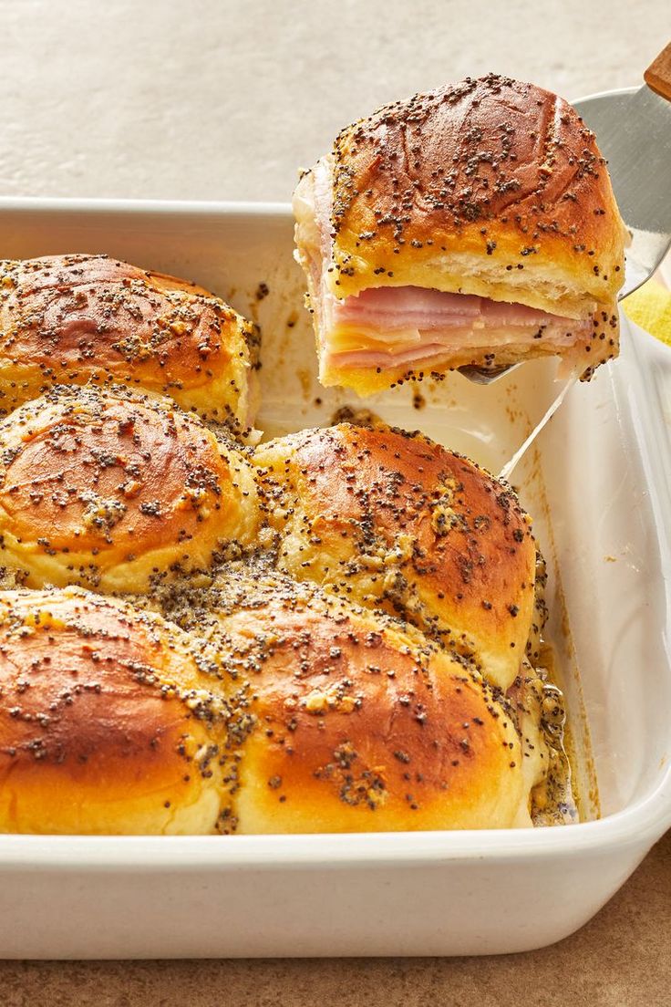 ham and cheese sliders in a casserole dish being lifted with a spatula