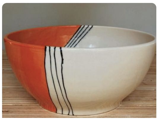 an orange and white bowl sitting on top of a wooden table