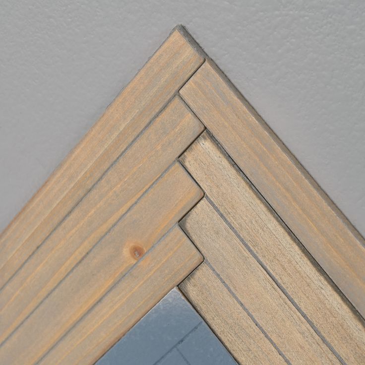 the corner of a mirror with wood grains on it's sides and a white wall behind it