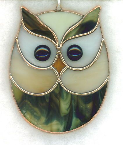 an owl shaped glass pendant hangs on a chain