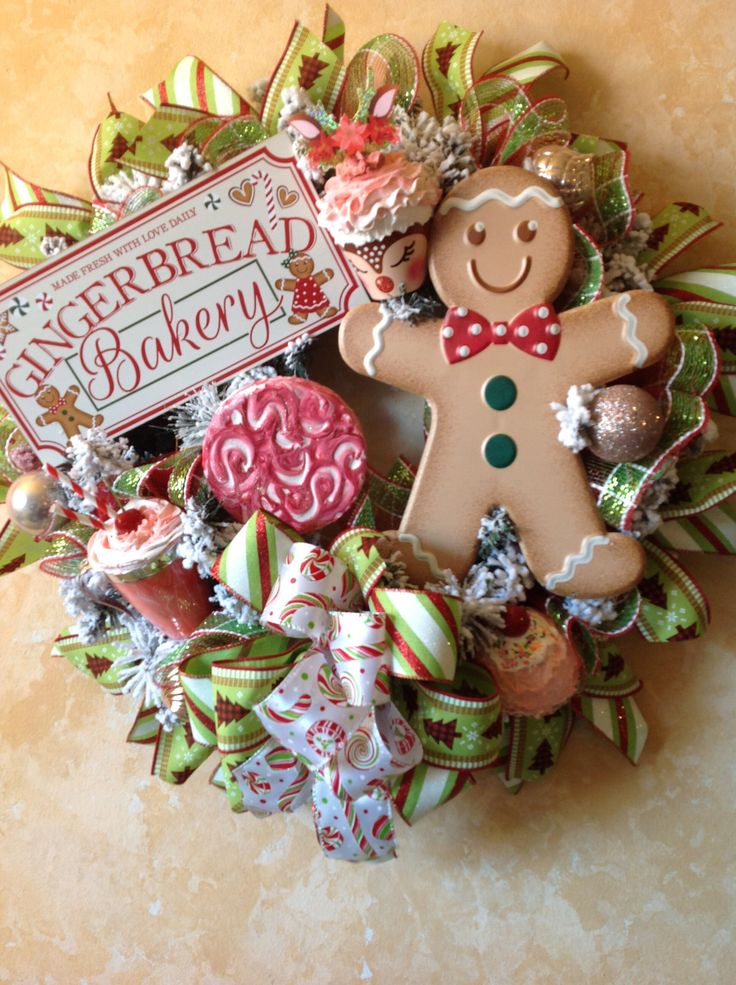 a christmas wreath with a gingerbread man and candy canes in the center, on a wall