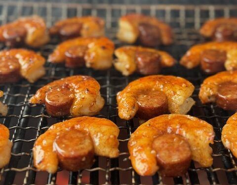 hot dogs and sausages cooking on a grill