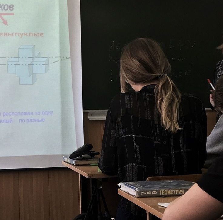 two women standing in front of a class room with a projector screen behind them