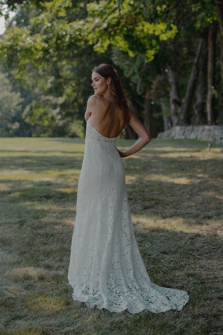 the back of a woman's wedding dress is shown in an open grassy field