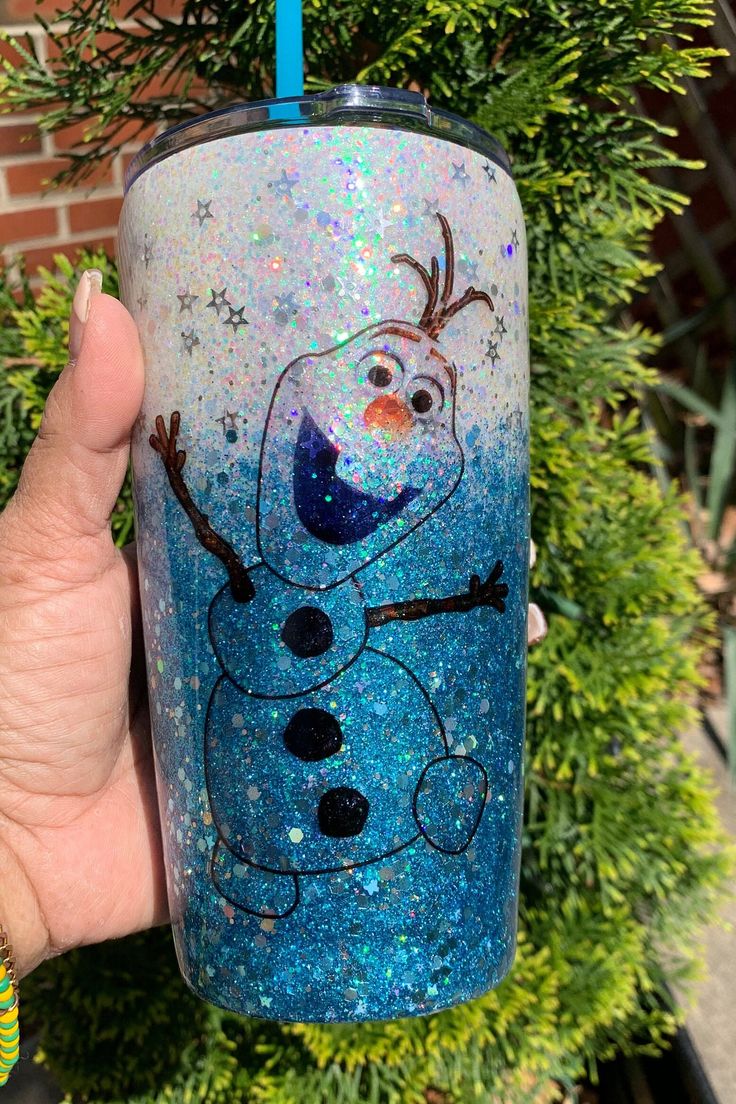 a hand holding up a blue cup with a frozen snowman on it