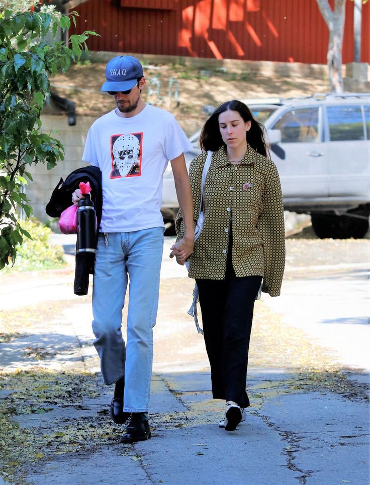 a man and woman walking down the street holding hands