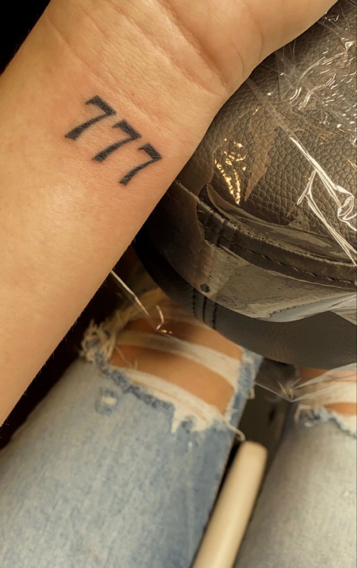 a woman's arm with a tattoo on it that has the letter e in cursive writing