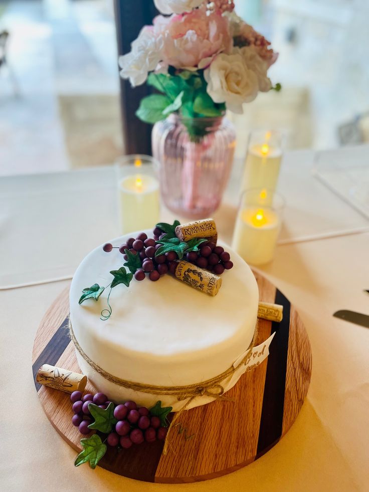 there is a cake with grapes on it and flowers in the vase next to it