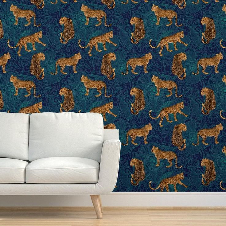 a couch sitting in front of a wallpaper with lions on it