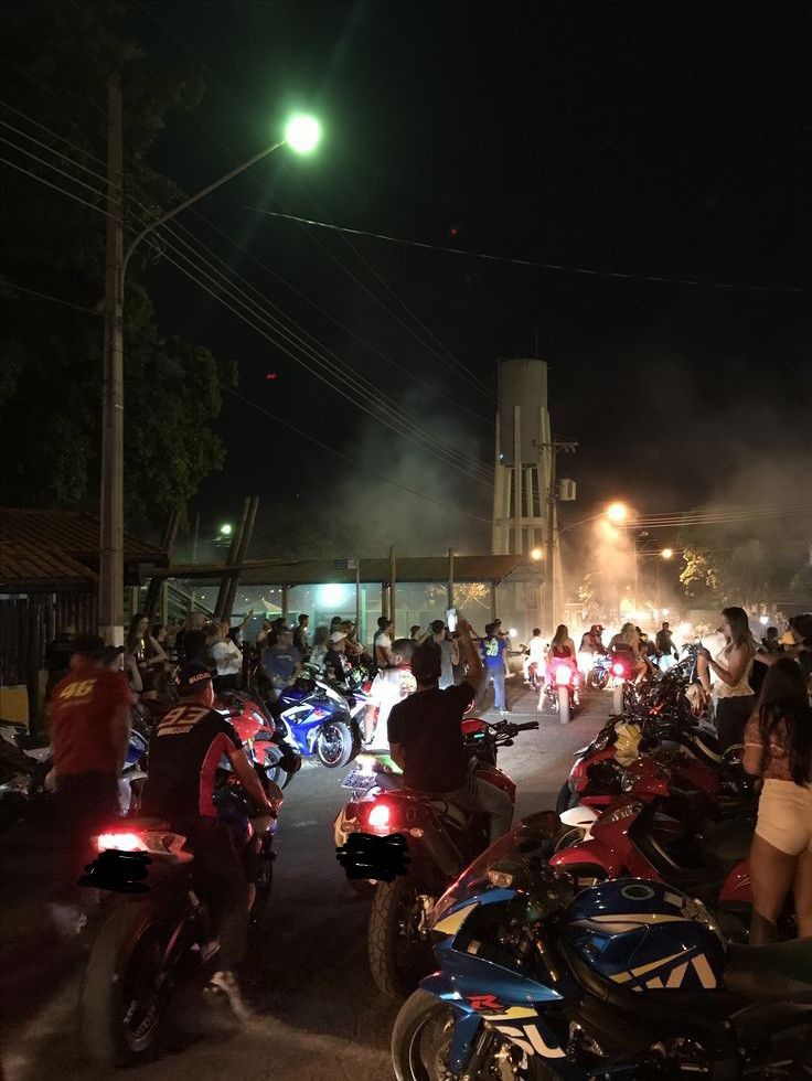 a group of people riding motorcycles down a street at night