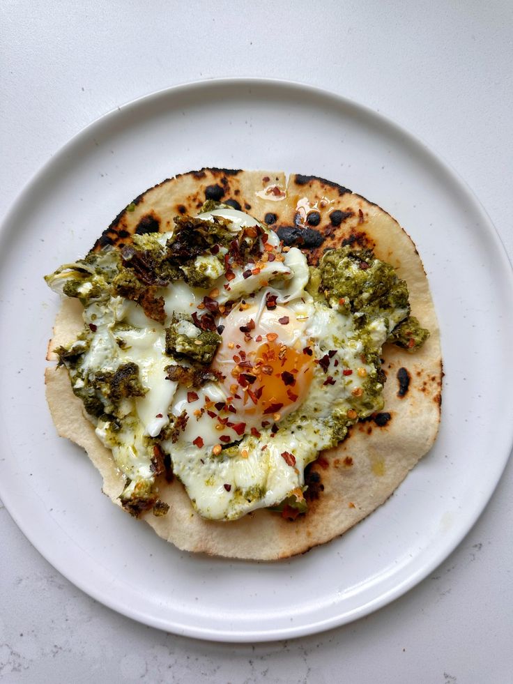 an egg and broccoli pita on a white plate with a fork next to it