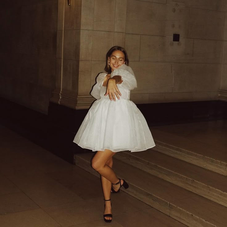 a woman in a white dress is walking down some stairs and posing for the camera